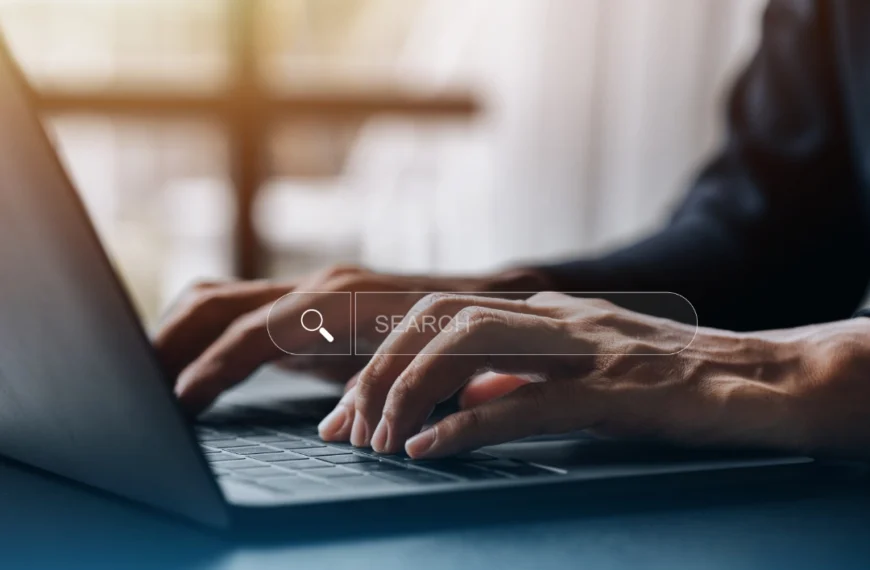 Primer plano de las manos de una persona escribiendo en un teclado portátil con una barra de búsqueda virtual superpuesta, resaltando el Diseño Web que inspira Confianza.