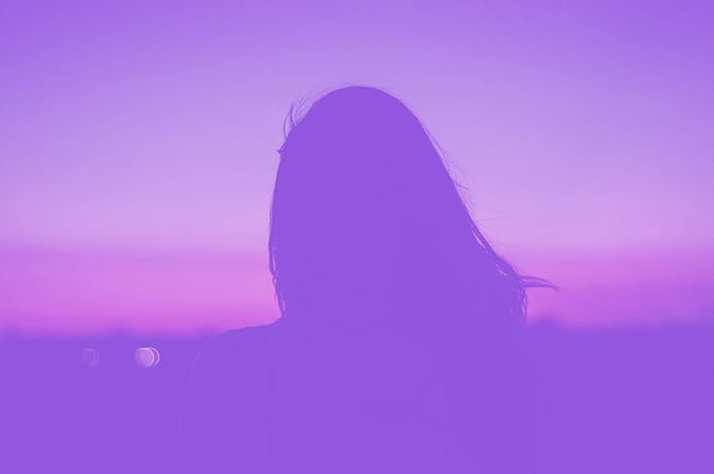 img-ter-ind-5f2 Silueta de una persona con cabello largo contra un cielo degradado de color púrpura y rosa al anochecer, perfecta para una llamativa página de inicio de marketing digital.