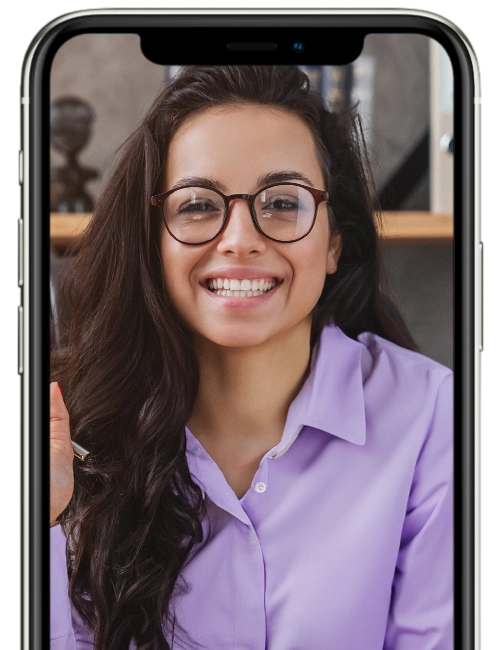 img-ter-ind-6b Una persona con gafas y una camisa violeta claro sonríe mientras es fotografiada con un teléfono inteligente, encarnando la cara amigable de su próxima campaña de marketing online.