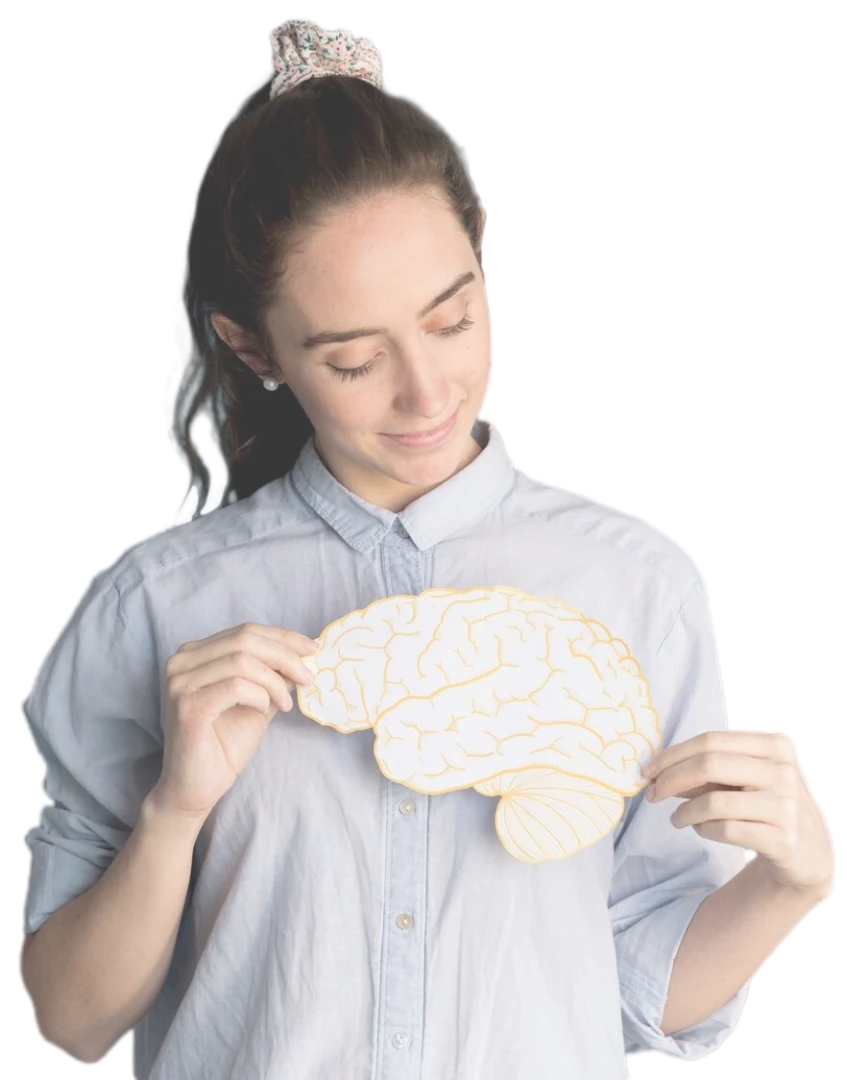 img2-perfil-psic-5 Mujer con camisa azul sosteniendo un objeto con forma de cerebro, sonriendo suavemente, con un fondo borroso.